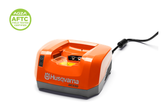 Vista frontal de un cargador de baterías Husqvarna QC330 con cable de alimentación; Insignia certificada AGZA AFTC.