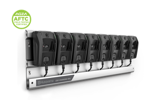 Husqvarna C80 charging rail with eight wall-mounted battery chargers, studio angled view.