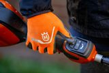 A person wearing work gloves operating a Husqvarna product with a control panel.