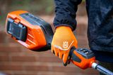 A person holding a Husqvarna product, showcasing the battery compartment.