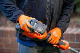 A person holding a Husqvarna product, showcasing the battery compartment.
