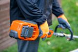 A person holding a Husqvarna product, showcasing the battery compartment.