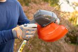 A person holding a string trimmer, showcasing the guard and handle.
