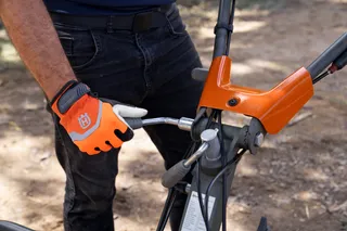 Uma pessoa que ajusta a barra de direção de um produto no exterior, usando luvas de trabalho.