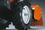 Primer plano de la rueda de un cortacésped con un neumático robusto y un equipo de corte.