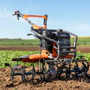 Обертальний культиватор Husqvarna, розташований на обробленому полі й готовий до підготовки ґрунту.