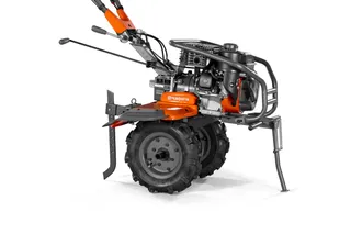 Вид збоку на культиватор Husqvarna з видимим двигуном і ручками керування.
