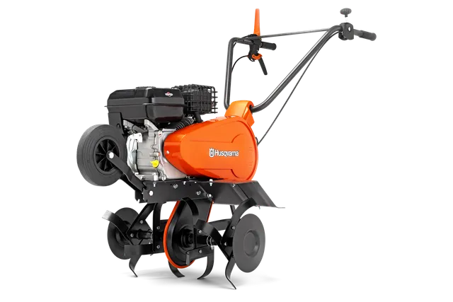 Seitenansicht einer Husqvarna Motorhacke mit sichtbaren Zinken und Lenker.