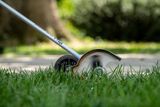 A grass trimmer in use, cutting the edge of a lawn.