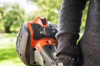 Eine Person, die ein Husqvarna-Gerät in der Hand hält und das Motorteil präsentiert.