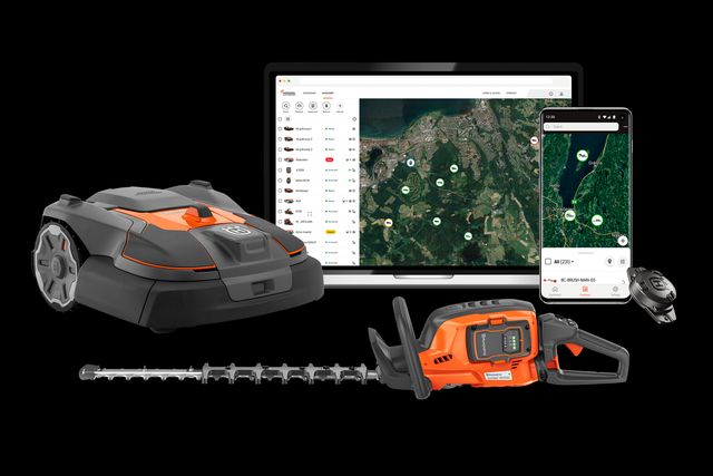 A robotic lawn mower and a hedge trimmer displayed in front of a laptop and smartphone showing a garden management app.