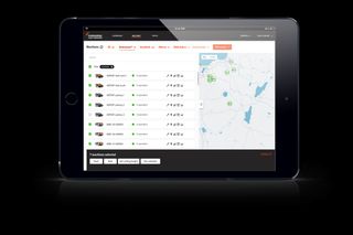 Tablet displaying a fleet management system interface with a map and machine status list.