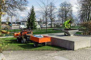 Persona darba aprīkojumā, kas izkrauj materiālus no komunālā transportlīdzekļa parka vidē.