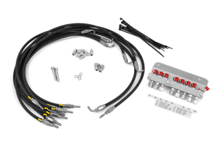 Pohled shora na různé hydraulické hadice a spojky, včetně stahovacích pásků a kovových armatur.