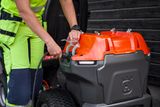 A person preparing to charge an electric Husqvarna frontmower.