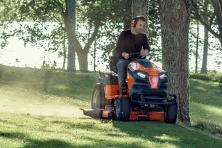 O persoană care tunde gazonul cu o mașină de tuns iarba într-un parc.