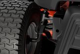 Close-up view of a ride-on mower's rear wheel and suspension system.
