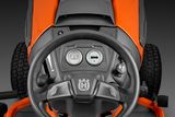Top view of a ride-on mower's steering wheel and dashboard with control indicators.