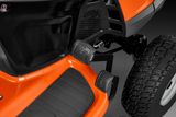 Close-up view of a ride-on mower's foot pedals and wheel.
