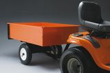 Side view of a ride-on mower with an attached utility trailer.
