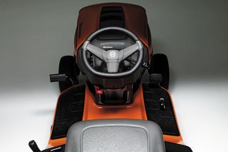 Vedere de sus a volanului și scaunului unei mașini de tuns iarba Husqvarna.