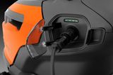 Close-up view of a Husqvarna product's charging port with cable connected.