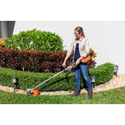 Une personne utilise un coupe-bordure pour border une pelouse de jardin.