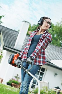 A person using a garden trimmer in a residential backyard.