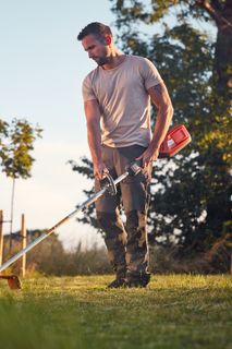 Ένα άτομο που χρησιμοποιεί ένα χορτοκοπτικό για να διατηρήσει ένα γκαζόν κήπου.