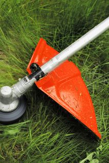 Ein Rasentrimmer, der in einer Gartenumgebung durch hohes Gras schneidet.