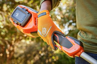 A person holding a Husqvarna product, showcasing the battery compartment.