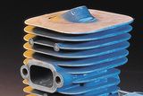 Close-up of a metal cylinder component with multiple fins and an exhaust port.