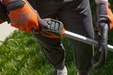 A person adjusting the controls on a Husqvarna garden tool, wearing work gloves.