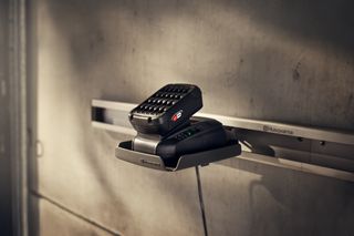 Chargeur de batterie Husqvarna monté sur un mur dans un garage.