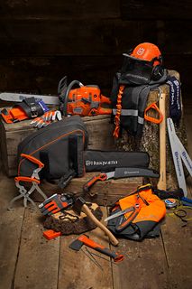 คอลเลกชันของอุปกรณ์เลื่อยโซ่ยนต์ Husqvarna และอุปกรณ์ทํางานที่จัดแสดงบนท่อนไม้