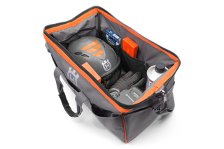 Top view of a Husqvarna tool bag containing a helmet, gloves, and various accessories.
