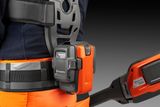 En person iført arbejdstøj med en Husqvarna-batteripakke fastgjort til en sele.