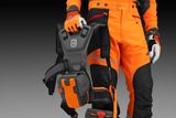 Personen med en Husqvarna-batterirygsæk, iført arbejdstøj.