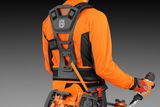 Set bagfra af en person, der bærer en Husqvarna-sele med et elværktøj påsat.