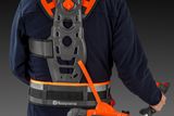 Set bagfra af en person, der bærer en Husqvarna-sele og holder et elværktøj.