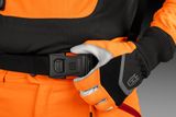 Nærbillede af en person iført arbejdshandsker, der fastgør et bæltespænde med Husqvarna-logo.