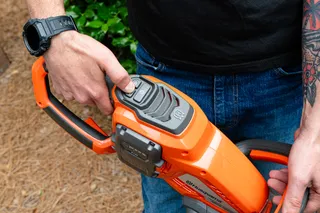 A person holding a Husqvarna product, showcasing the battery compartment.