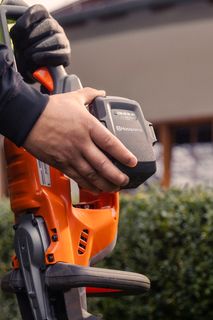 Osoba koja drži Husqvarna proizvod, izlažući pretinac za baterije.