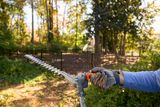 Une personne utilisant un taille-haie dans un jardin.