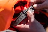 Close-up van handen die een hoofdband met maatmarkering in een werkhelm aanhalen.