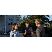 Two people in work wear discussing with a man in a garden setting.