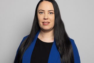 Edestä katsottava studion pääkuva henkilöstä, jolla on pitkät hiukset, kasvot sumennettuina, neutraalilla harmaalla taustalla.