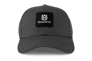 Vooraanzicht van een pet met Husqvarna-logo en logopatch.