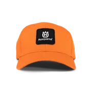 Vooraanzicht van een oranje pet met Husqvarna-branding.