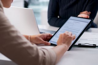 A person reviewing a contract on a tablet during a business meeting.